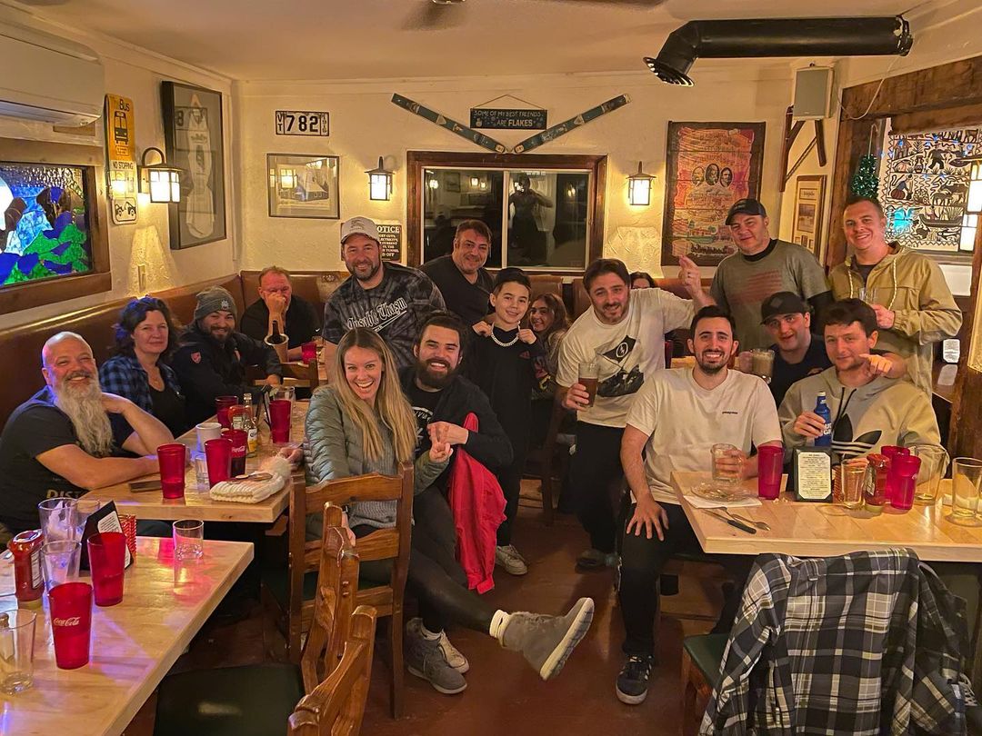 Group outing of about 15-20 people, some children, socializing and having dinner after a day on the slopes.