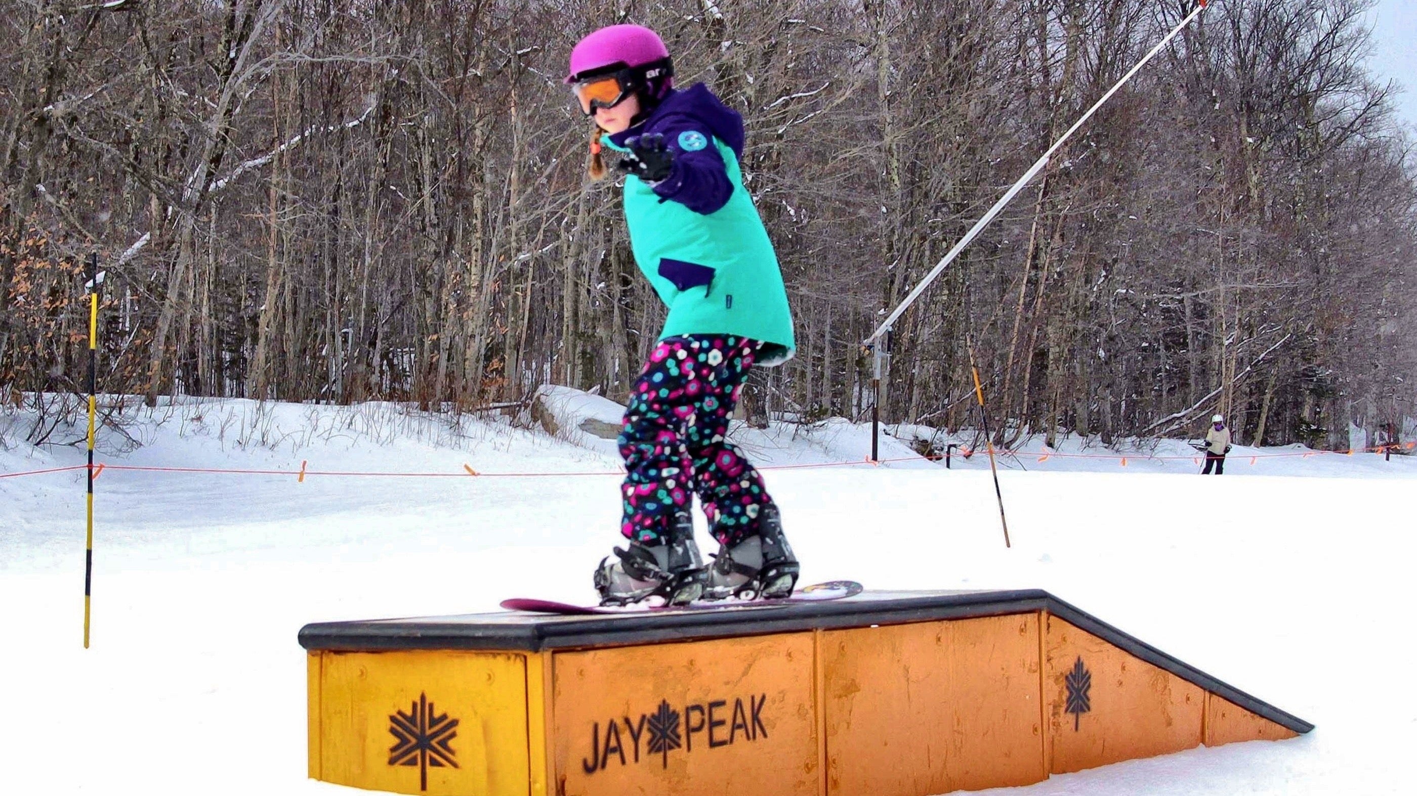 Young girl snowboarder balancing on a platform.