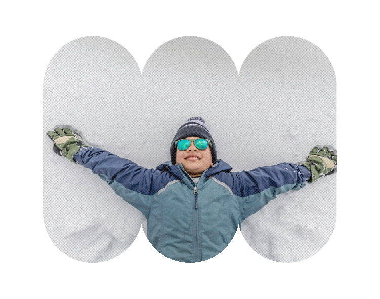 Smiling young boy laying in the snow like a snow angel. Wearing a blue winter coat, olive green gloves, beanie, and sunglasses to play in the snow.